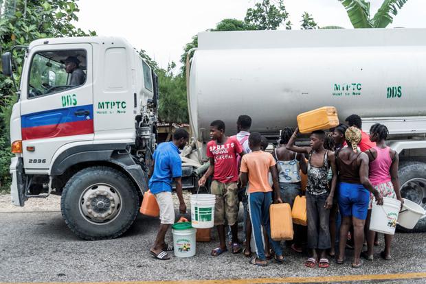 People gather near a water truck after the earthquake in Camp-Perrin, Haiti. (REGINALD LOUISSAINT JR / AFP).