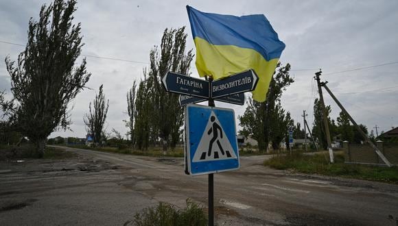 Una fotografía tomada el 27 de septiembre de 2022 muestra la bandera ucraniana ondeando en una calle de la aldea recientemente liberada de Vysokopillia, región de Kherson. (Foto de Genya SAVILOV / AFP)