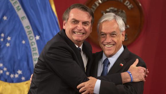 El expresidente chileno, Sebastián Piñera (derecha), abraza a su homólogo brasileño, Jair Bolsonaro (i), durante una conferencia de prensa conjunta en el Palacio Presidencial de La Moneda en Santiago, el 23 de marzo de 2019. (Foto de CLAUDIO REYES / AFP)