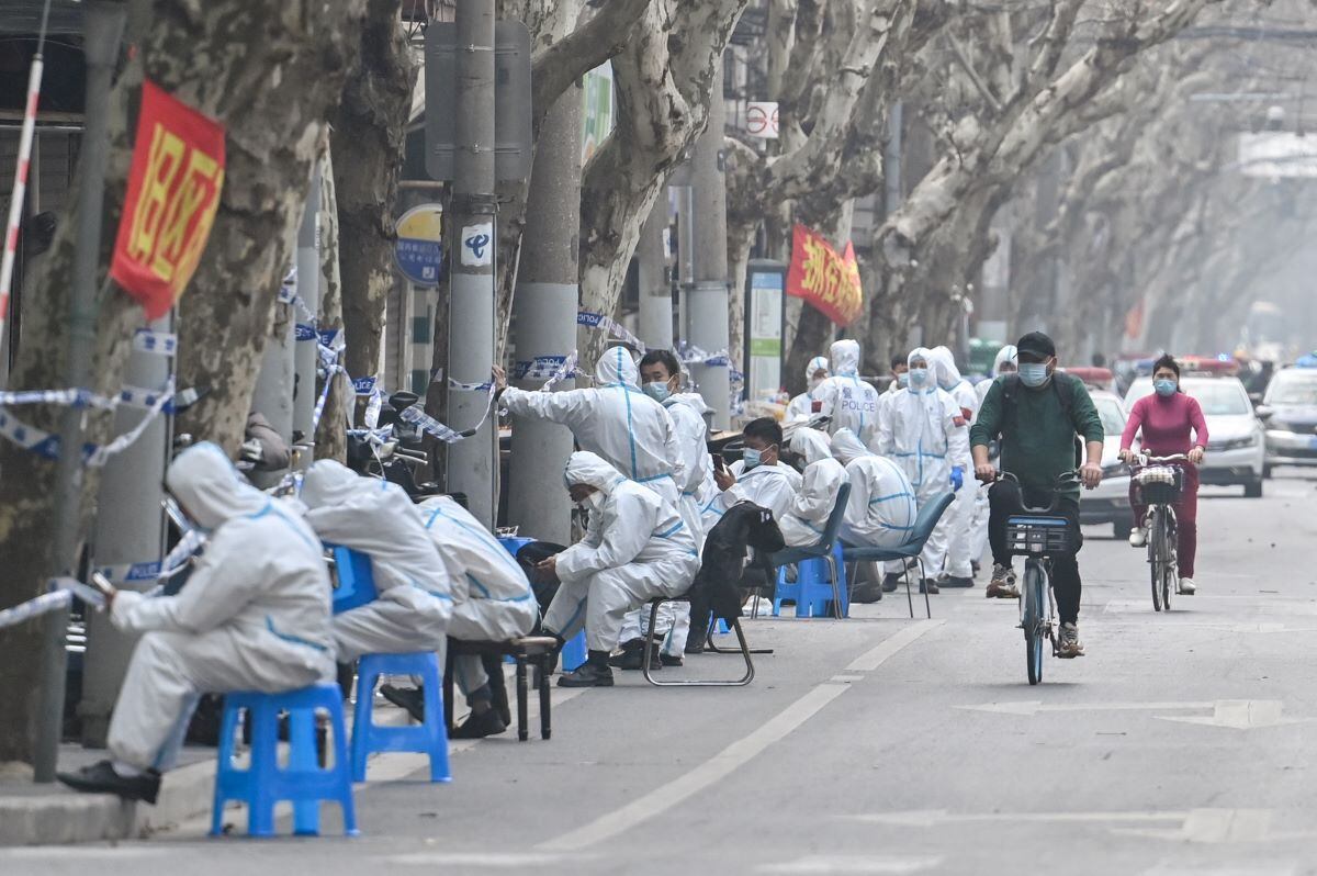 Workers in protective clothing close some areas after the detection of new cases of covid-19 coronavirus in Shanghai, China, on March 14, 2022. (Héctor RETAMAL / AFP).