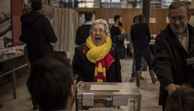 A woman wearing the Spanish and Catalan red and yellow colors approaches the ballot box to cast her vote for the Catalan regional election in Barcelona, Spain, on Thursday, Dec. 21, 2017. Catalans are choosing new political leaders in a highly contested election called by central authorities to quell a separatist bid in Spain's northeastern region. (AP Photo/Santi Palacios)