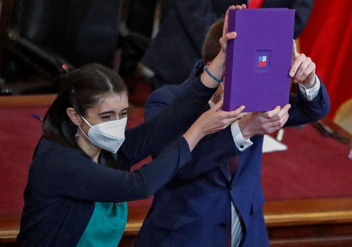 The president and vice president of the Chilean Constituent Convention, María Elisa Quinteros and Gaspar Domínguez, respectively, raise the final draft of the proposal for the new Constitution, on July 4, 2022. (JAVIER TORRES / AFP).