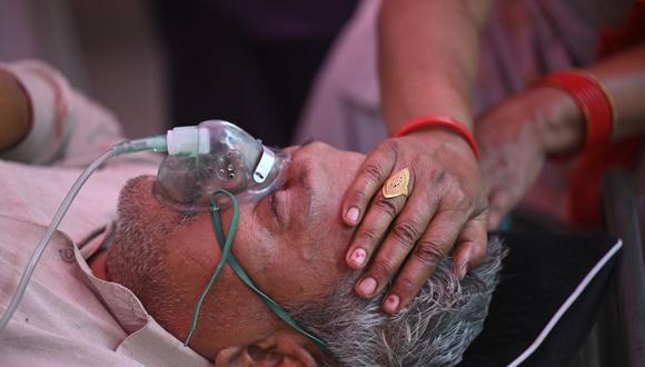 Un paciente de coronavirus que respira con la ayuda de oxígeno es tratado en una carpa en Ghaziabad, India, el 2 de mayo de 2021. (Foto de SAJJAD HUSSAIN / AFP).