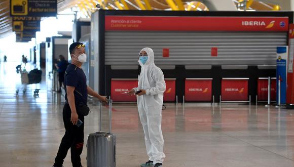 Dos personas esperan después de registrarse para un vuelo con destino a Beijing en el aeropuerto de Barajas, en Madrid, España, el 20 de junio de 2020, en plena pandemia de coronavirus. (PIERRE-PHILIPPE MARCOU / AFP).