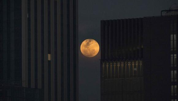 La superluna se está viendo por distintas partes del planeta. En la imagen se aprecia a la Luna entre dos edificios de oficinas en Bangkok, Tailandia. (Foto: AFP)