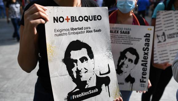 La gente sostiene carteles con la imagen del empresario colombiano Alex Saab, extraditado a Estados Unidos. (Federico PARRA / AFP).