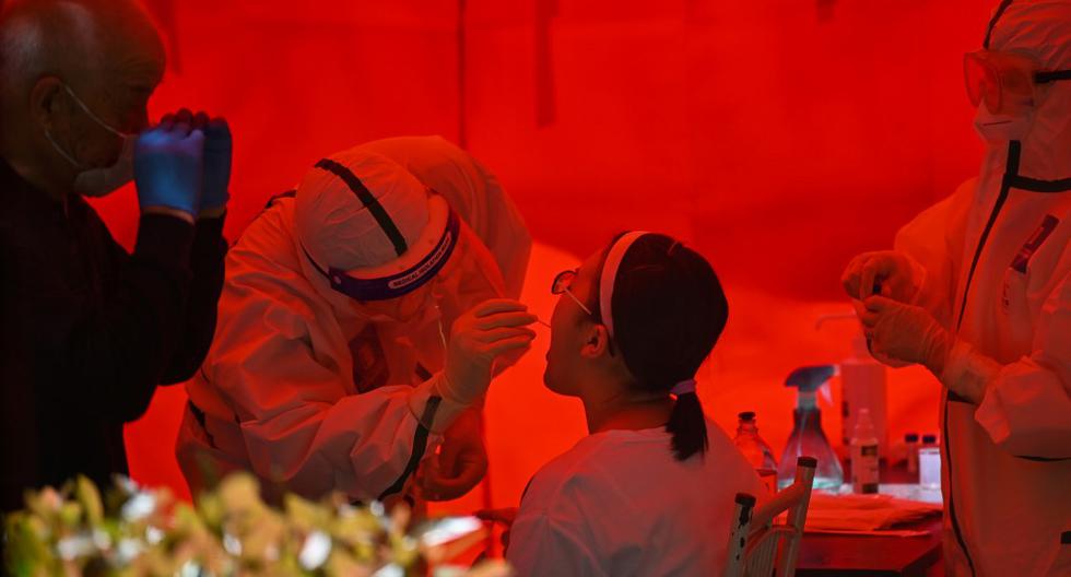 Un trabajador médico toma una muestra para descartar un posible caso de COVID-19 a una mujer en Wuhan. Las autoridades de la ciudad han ordenado realizar pruebas en masa para los 11 millones de residentes después de que surgió un nuevo grupo de casos. (Héctor RETAMAL / AFP)