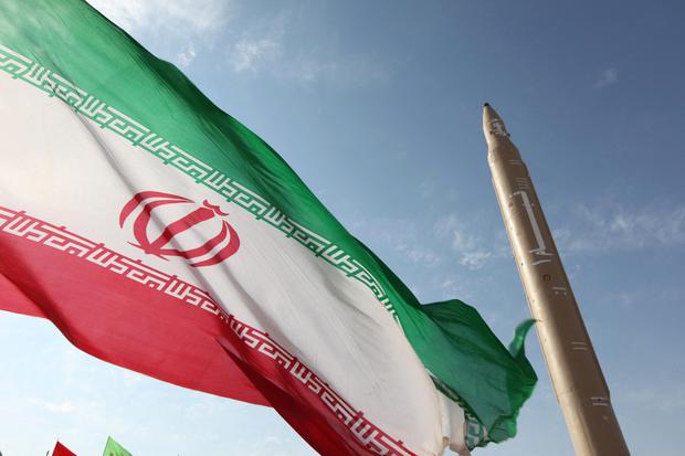 Una fotografía tomada el 20 de agosto de 2010 muestra una bandera iraní ondeando en un lugar no revelado de la república islámica junto a un misil tierra-tierra Qiam-1. (FOTO AFP/VAHID REZA ALAEI).
