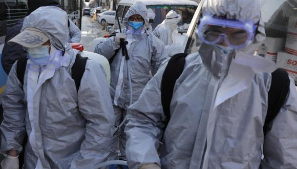 Trabajadores que usan trajes protectores se reúnen después de desinfectar un área residencial en Beijing, China, para prevenir la expansión del coronavirus. (EFE / EPA / WU HONG).