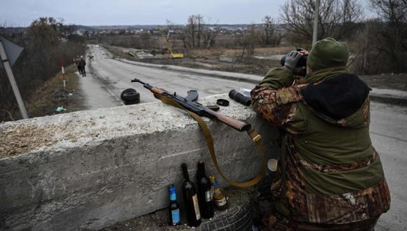 Un militar ucraniano mira a través de binoculares hacia la ciudad de Stoyanka en un puesto de control antes del último puente en la carretera que conecta Stoyanka con Kiev. (Foto: ARIS MESSINIS / AFP)