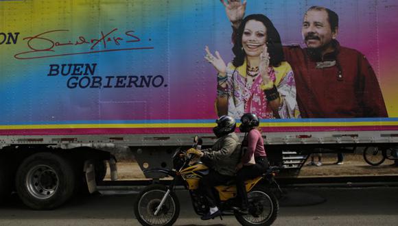 Un motociclista pasa junto a una pancarta del presidente de Nicaragua -y candidato presidencial- Daniel Ortega y su esposa y compañera de fórmula Rosario Murillo, colocada en una clínica móvil, en Masaya. (Foto: Oswaldo Rivas / AFP).
