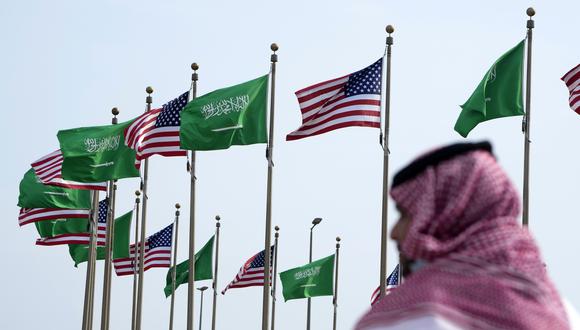 Un hombre de pie bajo las banderas de Estados Unidos y Arabia Saudita antes de la visita del presidente de Estados Unidos, Joe Biden, en una plaza en Jeddah, Arabia Saudita.