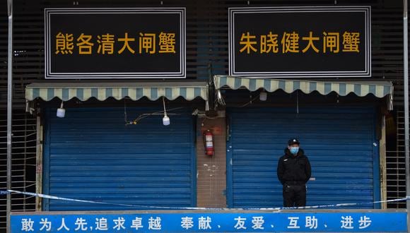 En esta foto de archivo tomada el 24 de enero de 2020, un guardia de seguridad se encuentra frente al mercado mayorista de mariscos de Huanan, donde se detectó el coronavirus en Wuhan. Foto referencial: archivo AFP / Hector RETAMAL