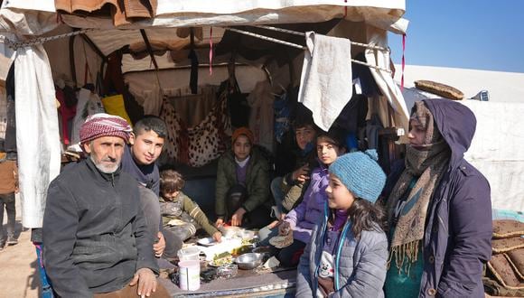 Una familia siria se reúne en un vehículo donde han estado viviendo después del terremoto del 6 de febrero que azotó a Turquía y Siria, en la ciudad rebelde de Jindayris el 12 de febrero de 2023. (Foto de Rami al SAYED / AFP)