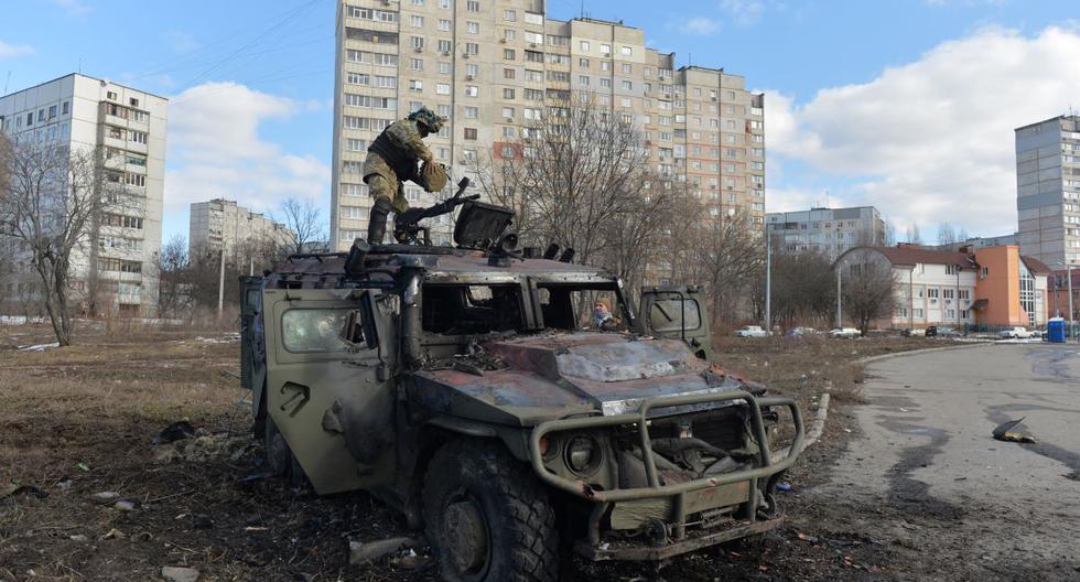 Un combatiente de Defensa Territorial de Ucrania examina un vehículo de infantería de Rusia GAZ Tigr destruido en la ciudad de Kharkiv, el 27 de febrero de 2022. (Serguéi BOBOK / AFP).
