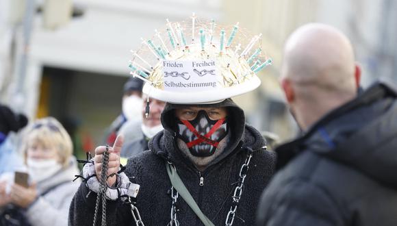 A protester wears a hat spiked with syringes reading "Peace - Freedom - Self-Rule" during a demonstration against the Austrian government's measures taken in order to limit the spread of the coronavirus, on December 12, 2021 in Graz, Austria, amidst the novel coronavirus / Covid-19 pandemic. - The Graz demonstration is only one in a string of huge weekend protests since Austria in November 2021 became the first EU country to say it would make Covid vaccinations mandatory. (Photo by ERWIN SCHERIAU / APA / AFP) / Austria OUT
