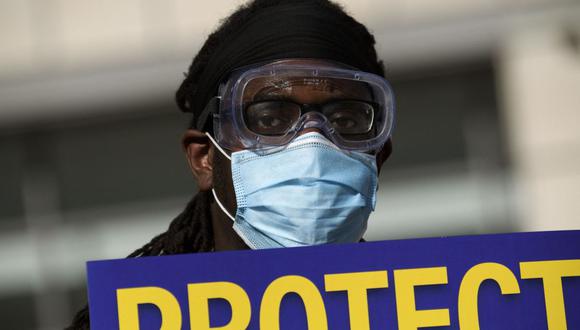 El Dr. Salam Beah usa una mascarilla y un cartel en apoyo de los médicos residentes, pasantes y becarios de UCLA Health mientras protestan por la mejora de las pruebas de Covid-19 y las políticas de seguridad en el lugar de trabajo, el 9 de diciembre de 2020. (Foto de Patrick T. Fallon / AFP).
