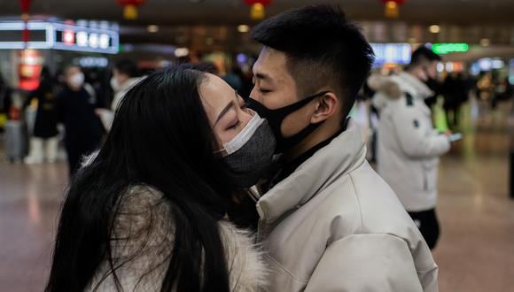 Una pareja, provista de mascarillas, se dan un beso de despedida en la estación de tren de Beijing, China, en enero de este año. (Photo by NICOLAS ASFOURI / AFP)