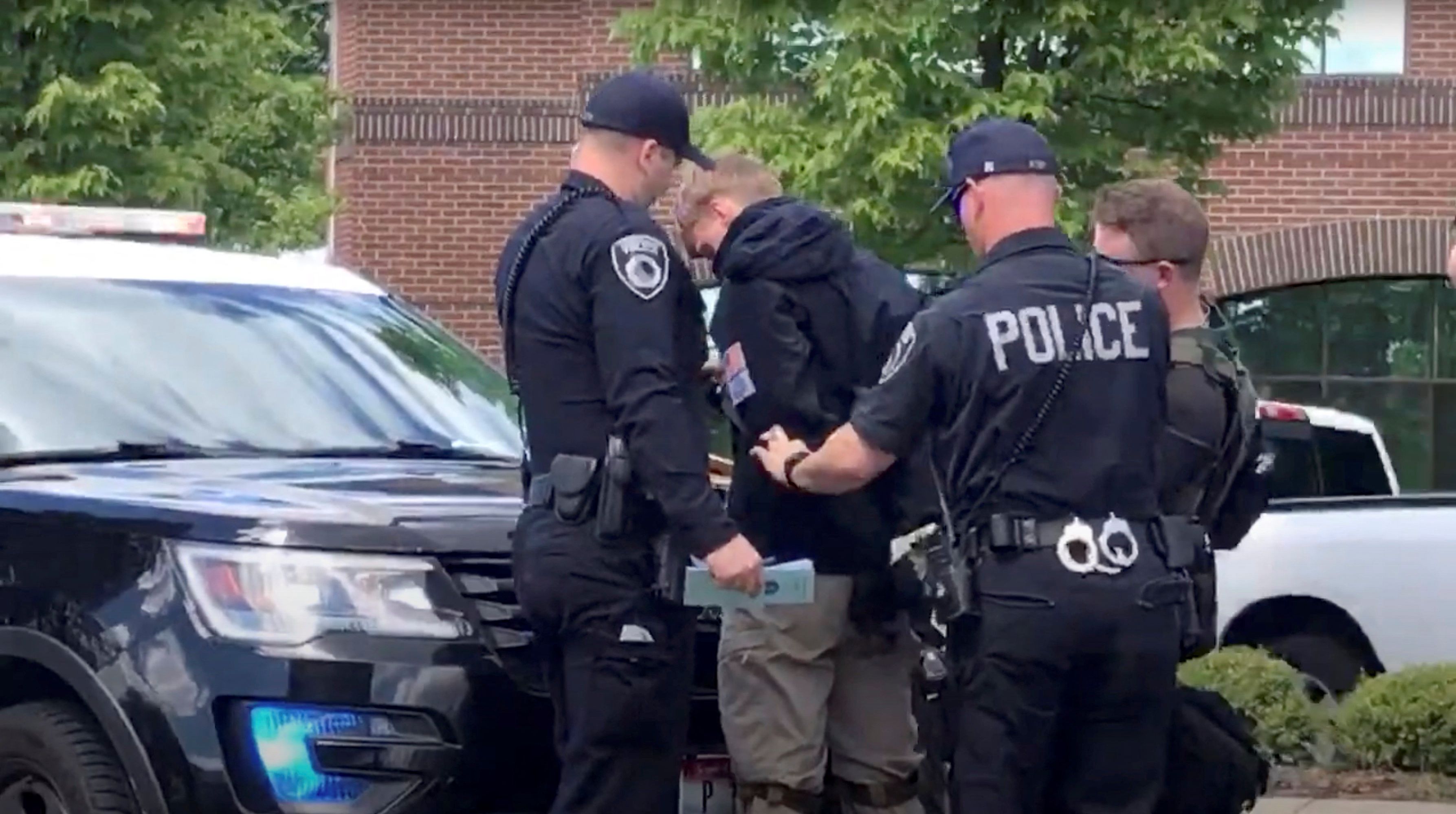 A man is detained as police in riot gear protect a group of men, who police say are among 31 arrested for conspiracy to riot and are affiliated with the Patriotic Front group, after they were found in the back of a van U Haul in the near of a Pride event in Coeur d'Alene, Idaho, USA