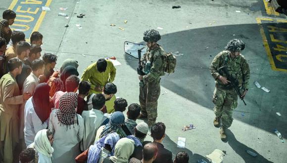 Soldados estadounidenses montan guardia mientras los afganos esperan en el aeropuerto de Kabul después de un final asombrosamente rápido de la guerra de 20 años de Afganistán. (Foto: Wakil Kohsar / AFP)