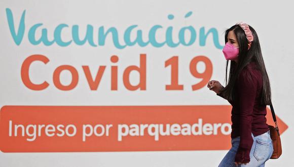 Una mujer pasa frente a un cartel que indica un punto de vacunación contra el coronavirus COVID-19 en Bogotá, Colombia, el 21 de diciembre de 2021. (DANIEL MUÑOZ / AFP).