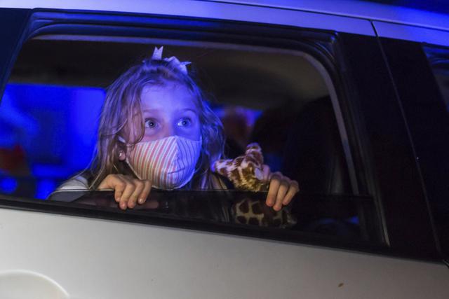 Una niña que usa una máscara protectora observa una actuación desde el interior de un automóvil, en el parque de diversiones temático de terror Hopi Hari, en el suburbio de Vinhedo de Sao Paulo, Brasil. (Foto AP / Carla Carniel).