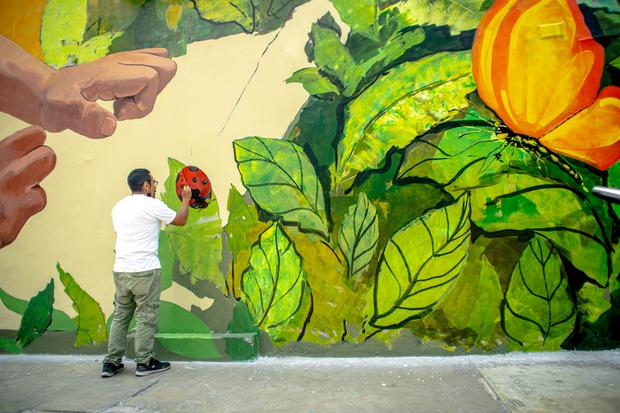 After the roller work, Domenak focuses on the details.  With a brush, he outlines a colorful ladybug on the foliage.  (PHOTO: CCE)