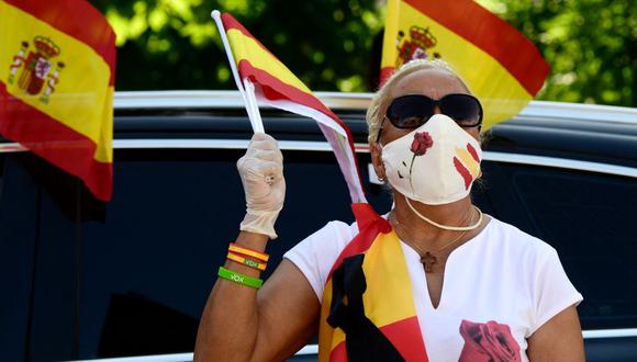 Una persona con una mascarilla ondea una bandera española durante una protesta en medio de la pandemia de coronavirus en Madrid, España, el 23 de mayo de 2020. (JAVIER SORIANO / AFP).