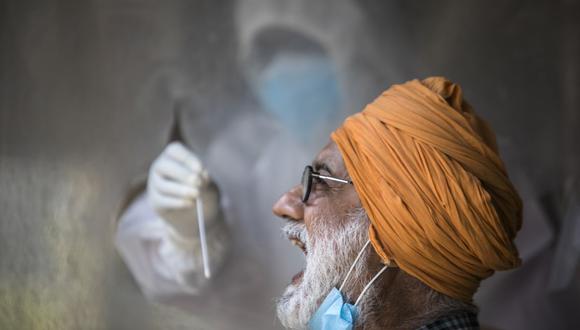 Un funcionario de salud recolecta una muestra de un hisopo de un hombre para analizar el coronavirus COVID-19 en un centro de pruebas de la India. (Foto de XAVIER GALIANA / AFP).