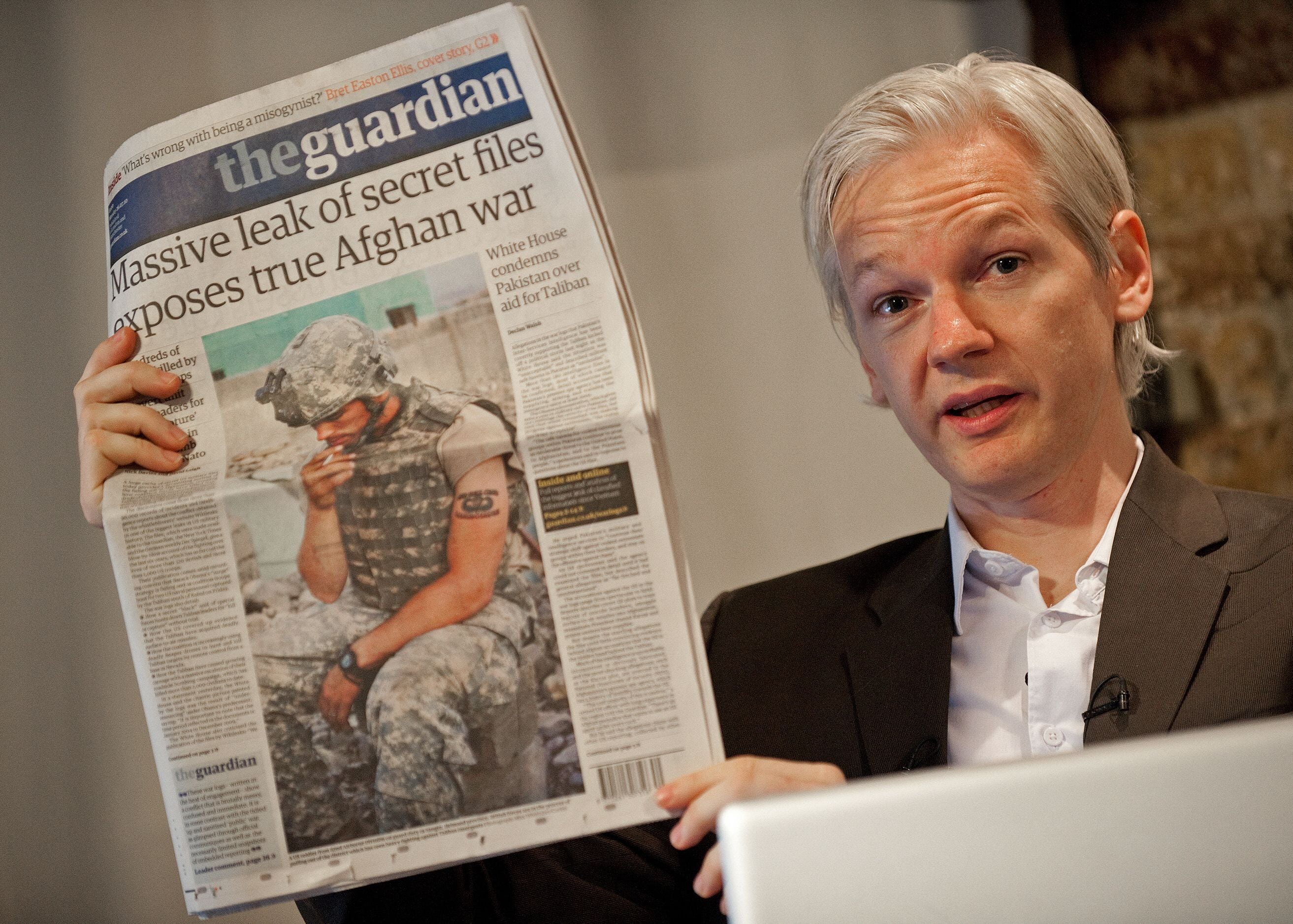 Julian Assange holds a copy of The Guardian newspaper during a press conference in London on July 26, 2010. (Photo by LEON NEAL/AFP).