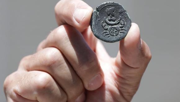 Jacob Sharvit, director de la unidad de arqueología subacuática de la autoridad de antigüedades de Israel, sostiene una moneda de 1.850 años que muestra el signo de Cáncer y la figura de la diosa de la Luna. (EFE/EPA/ABIR SULTAN).
