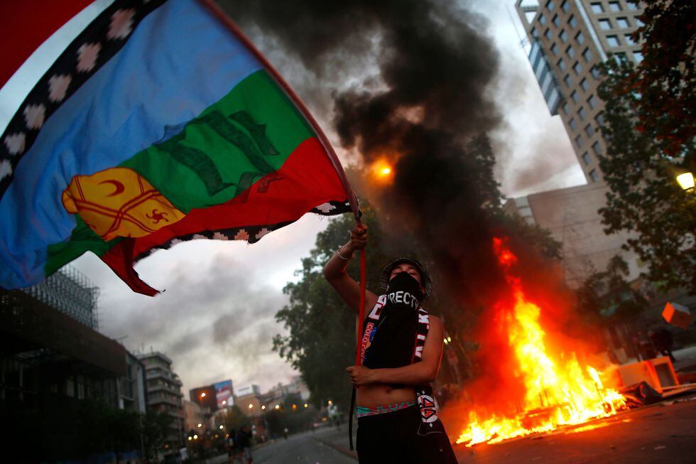 Un manifestante ondea una bandera indígena mapuche durante una protesta en Santiago. (AFP / Pablo VERA).