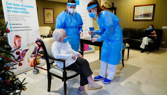 Una empleada del asilo de ancianos "El Viso" habla con Amalia González, de 96 años, antes de que le inyecten una dosis de la vacuna Pfizer-BioNTech COVID-19 en Madrid, España, el 7 de enero de 2021. (REUTERS/Juan Medina).