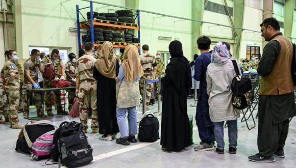 La gente espera a que los soldados revisen sus maletas en un centro de reunión y evacuación en la base aérea militar francesa 104 de Al Dhafra, cerca de Abu Dhabi luego de ser evacuada de Kabul como parte de la operación "Apagan". (Foto: BERTRAND GUAY / AFP).