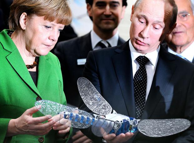 Angela Merkel and Russian President Vladimir Putin hold a self-contained "Dragonfly" at the Festo company booth as they tour the Hannover industrial fair on April 8, 2013 in Germany.  (RONNY HARTMANN / AFP).