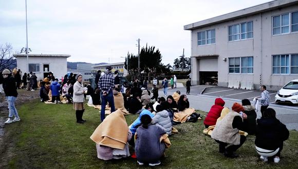 La gente se sienta al aire libre después de ser evacuada de los edificios en la ciudad de Wajima, prefectura de Ishikawa, el 1 de enero de 2024, después de que un gran terremoto sacudiera Japón. (Foto de Yusuke FUKUHARA / Yomiuri Shimbun / AFP).