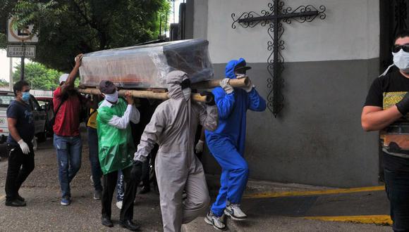 Familiares de una persona que falleció por el nuevo coronavirus, algunos con trajes protectores, llevan el ataúd envuelto dentro de un cementerio en el norte de Guayaquil, Ecuador. (Foto:  AP/Dolores Ochoa).