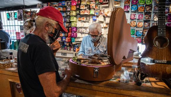 Un trabajador que usa una máscara protectora ayuda a un cliente en una tienda de música en Austin, Texas, EE.UU. (Foto: Sergio Flores / Bloomberg / Archivo).