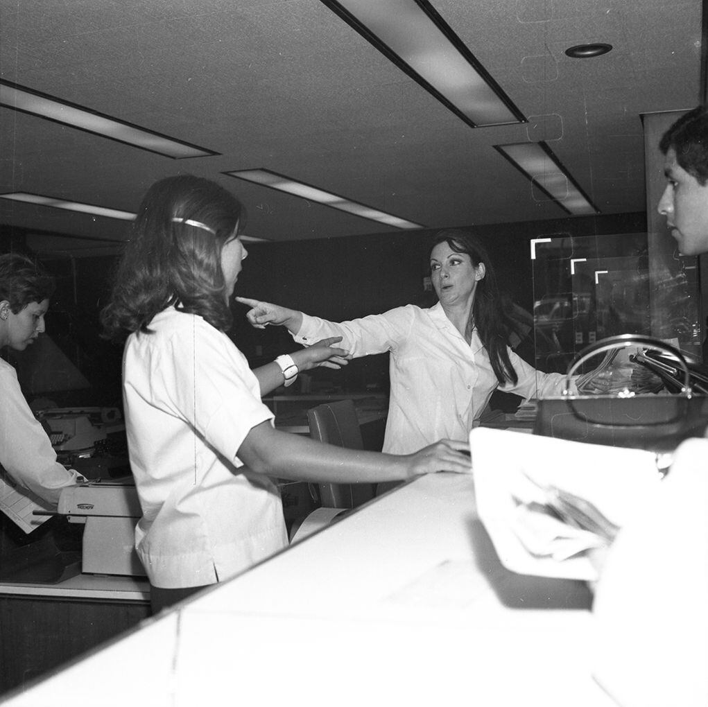 Instantes en que la cajera Maruja Alcalá Davis (derecha) explica cómo sucedió el robo mientras le hacia una pregunta a su compañera de trabajo. (Foto: GEC Archivo Histórico)