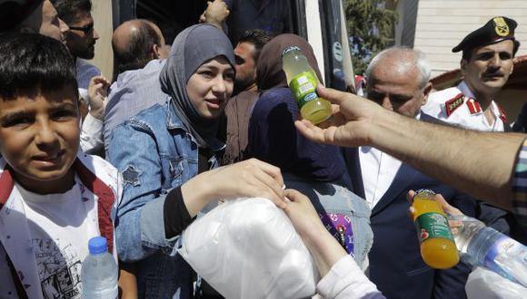 Refugiados sirios reciben ayuda alimentaria en su camino a casa en el paso fronterizo de Jdedeh Yabous, Siria. Gobierno prometió garantizar el regreso seguro de los refugiados. (Fuente: AP)