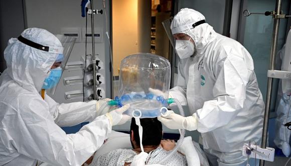 Los miembros del personal médico ayudan a un paciente a usar una nueva tecnología no invasiva que puede reducir la necesidad de intubación en la unidad de cuidados intensivos (UCI) Covid-19 en el Instituto de Cardiología Clínica (ICC) en Roma. (Foto: Alberto PIZZOLI / AFP)