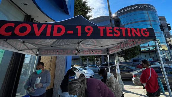 Las personas se registran para la prueba de coronavirus en una carpa situada en el edificio Writers Guild of America en la esquina de Third St y Fairfax Blvd, en Los Ángeles, California, Estados Unidos, el 3 de enero de 2022. (VALERIE MACON / AFP).