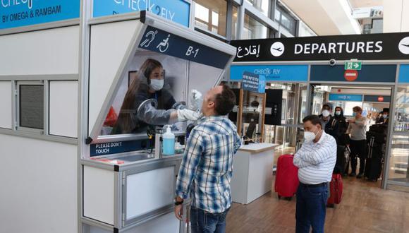 Un médico recolecta una muestra de hisopo de un viajero en un stand en el centro de pruebas rápidas de coronavirus COVID-19 en el Aeropuerto Internacional Ben Gurion de Israel en Lod. (Foto: AFP / JACK GUEZ).