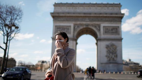 Una mujer que usa una máscara protectora contra el coronavirus camina cerca del Arco del Triunfo en París, Francia. (REUTERS / Gonzalo Fuentes).