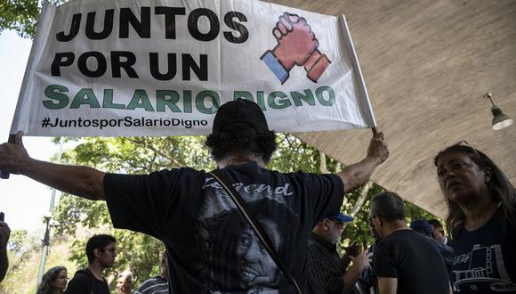 Un jubilado lleva un cartel que dice "Juntos por un salario digno" mientras participa en una protesta en Caracas el 2 de mayo de 2023. (Foto de Yuri CORTEZ / AFP)