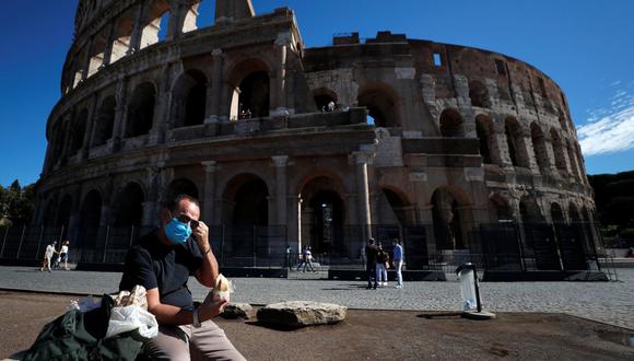 Un hombre con una mascarilla protectora se sienta cerca del Coliseo en Roma (Italia), el 8 de octubre de 2020. (REUTERS/Guglielmo Mangiapane).