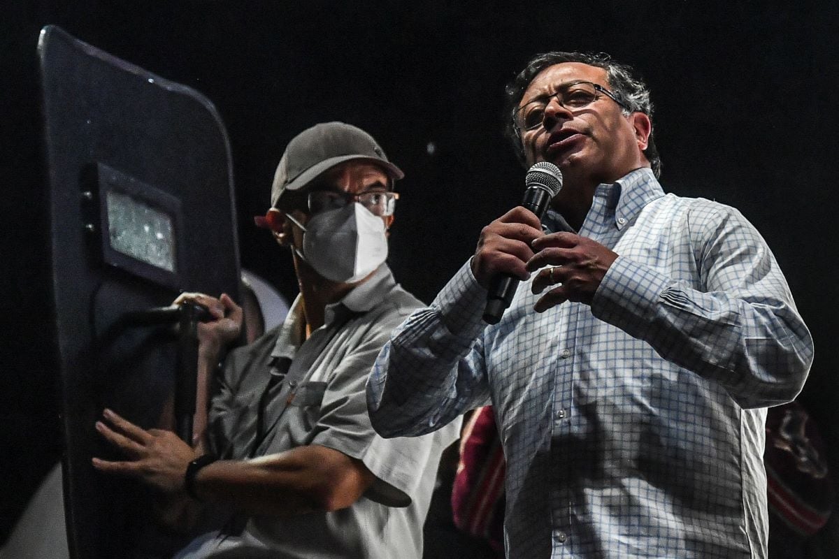 Left-wing presidential candidate Gustavo Petro is covered by a bodyguard holding a bulletproof shield during a rally in Medellin, Colombia, on May 20, 2022. (JOAQUIN SARMIENTO / AFP)