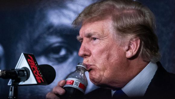 El ex presidente de Estados Unidos, Donald Trump, bebe un refresco mientras presenta el combate de boxeo Holyfield vs Belford en Hollywood, Florida, el 11 de septiembre de 2021. (CHANDAN KHANNA / AFP).
