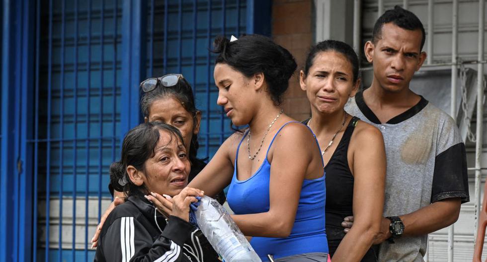 Residentes se consuelan mientras los rescatistas buscan a sus familiares desaparecidos entre los escombros de una casa destruida en Las Tejerias, estado de Aragua, Venezuela, el 9 de octubre de 2022. (Yuri CORTEZ / AFP).