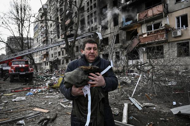 A man holds his dead cat in a blanket as he stands in front of an apartment building destroyed by Russian bombardment in the northwestern Obolon district of kyiv on March 14, 2022. (ARIS MESSINIS/AFP)
